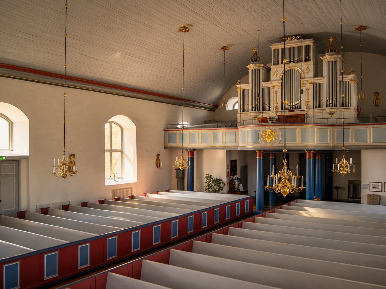 Interiör i Skatelövs kyrka med läktarorgel, bänkrader och kronljuskronor. Foto: Bernt Fransson.